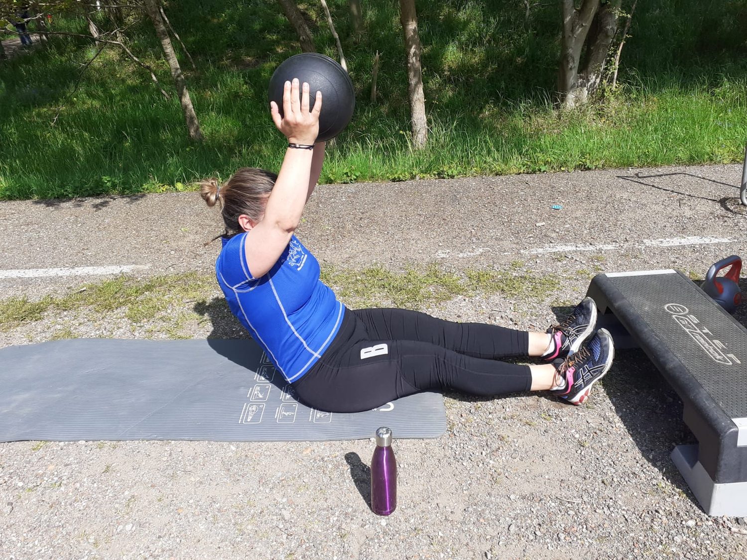 Vrouw traint op een mat met een bal boven het hoofd